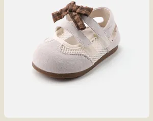 Detail of children's grey sandals with mesh upper and a brown plaid bow decoration