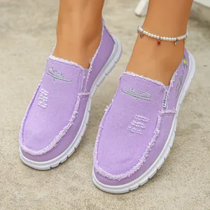 Close-up of purple canvas slip-on shoes with embroidered daisy and frayed edges