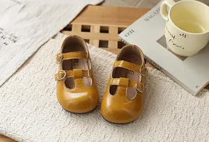 Detalle de zapatos T-strap de cuero amarillo para niñas con hebillas en un fondo de estilo vida