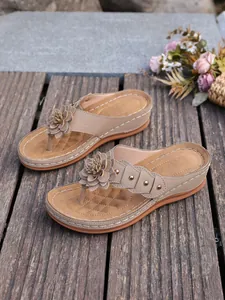 Detailopname van kaki sleehaksandalen met 3D-bloemaccent en metalen studs