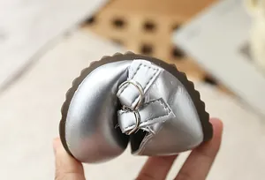 Detalle que muestra la flexibilidad y suela blanda del zapato de princesa plateado para niña.
