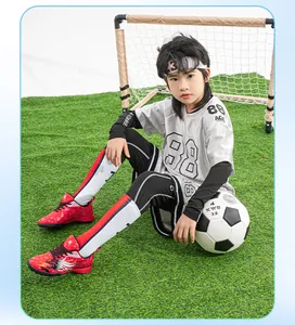 Close-up of children's red TF soccer shoes for artificial grass worn by a child