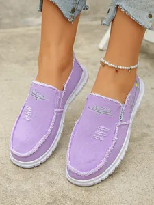 Detailed view of purple canvas slip-on loafers with frayed edges and embroidery