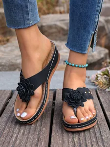 Detailopname van elegante zwarte sleehak-slippers met bloem- en klinknageldetails