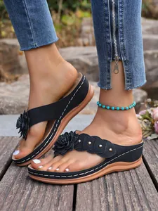 Stijlvolle zwarte dames sleehak slippers met bloem- en klinknageldetails op hout