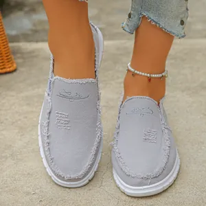 Close-up of grey frayed canvas slip-on loafers for women with white rubber sole
