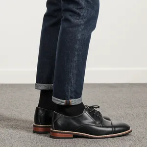 Detail shot of classic men's black leather Oxford shoes paired with denim jeans.
