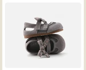 Close-up detail of grey girls' princess sandals with plaid bow and mesh side panels