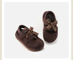 Detailed view of children's brown suede sandals with checkered bows and mesh panels