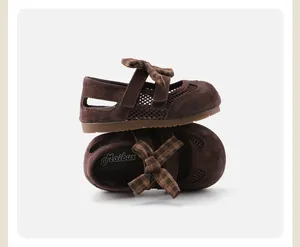 Detail view of brown girls' Mary Janes shoes with plaid bow and mesh side panels.