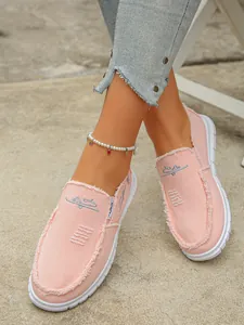 Detail view of pink canvas loafers for women with stylish frayed edges and embroidery.