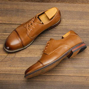 Detail view showing the polished leather texture of classic brown Oxford shoes on wood