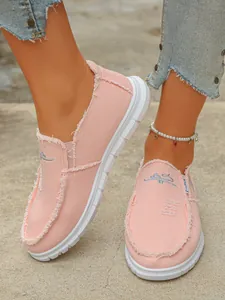 Detailed shot of women's pink frayed canvas slip-on shoes featuring embroidered vamp