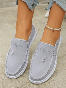 Close-up detail of stylish grey distressed canvas slip-on loafers for women on feet