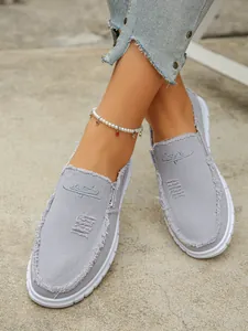 Grey canvas slip-on shoes with frayed details and white rubber soles for casual wear