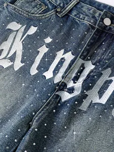 Close-up of men's denim shorts with gothic font print and shiny rhinestones