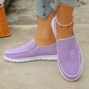 Detailed shot of stylish lavender canvas slip-on shoes with frayed edges on model's feet