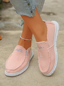 Detailed view of pink frayed canvas slip-on loafers styled with denim and pearl anklet