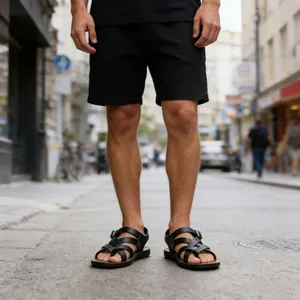 Close-up of men's black Roman sandals with multi-strap toe-ring design on street