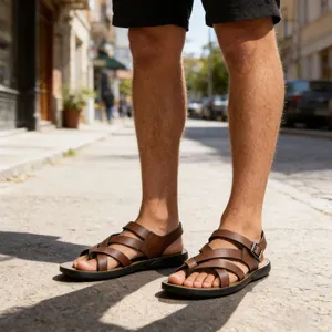 Stylish brown leather cross-strap Roman sandals for men shown in an outdoor urban street setting