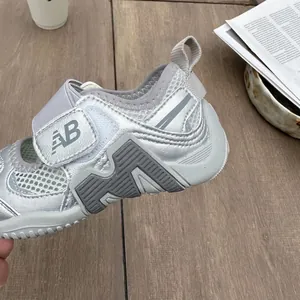 Close-up detail of silver breathable mesh kids' sandal featuring an AB logo velcro strap