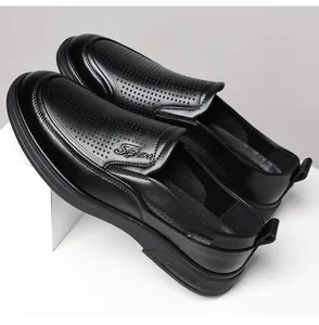 Macro view of black perforated leather loafers for men featuring a slip-on design