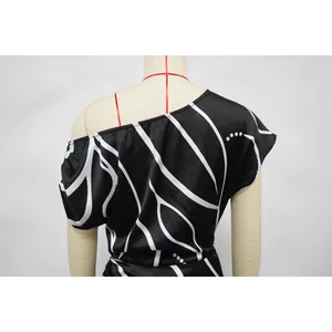 Gros plan du motif rayé géométrique noir et blanc sur le détail d'une robe à une épaule.