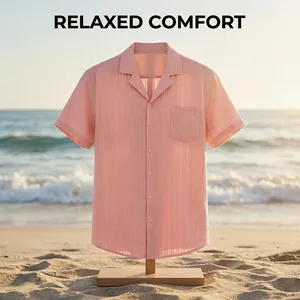 Detalle de camisa rosa de hombre con cuello cubano y textura de ondas en la arena de playa.