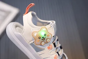 Close-up of baby sandal showing green LED light-up cartoon bear detail