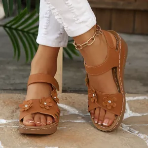 Detailansicht brauner Keilsandalen mit dekorativen Blumen und funkelnden Strasssteinen