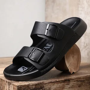 Vue rapprochée de sandales noires stylées pour hommes avec double boucle sur support en bois.