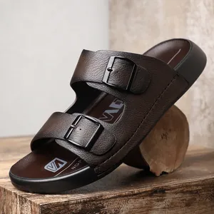 Gros plan détaillé de sandales en cuir marron pour hommes avec doubles boucles noires sur bois.
