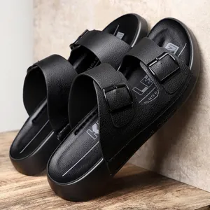 Gros plan de sandales noires pour hommes à double boucle, aspect cuir et semelle.