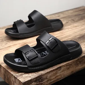Gros plan détaillé de claquettes noires pour hommes à double boucle et texture cuir premium