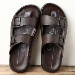 Gros plan de sandales pour hommes marron à double boucle avec assise plantaire texturée.