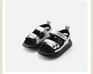 Détail de sandales de plage bébé argent et noir tendance avec brides velcro réglables