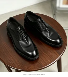 Vista detallada de zapatos de vestir de cuero negro para hombre sobre una mesa de madera