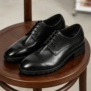 Zapatos derby clásicos de cuero negro para hombre sobre un taburete de madera vintage