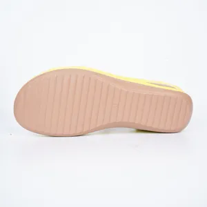 Detailed macro view of the anti-slip brown sole of these stylish yellow wedge sandals