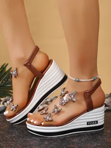 Detail view of elegant platform wedge sandals with sparkling rhinestone butterflies and clear straps