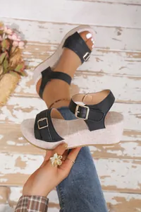 Close-up of women's black wedge sandals with gold buckle and woven platform