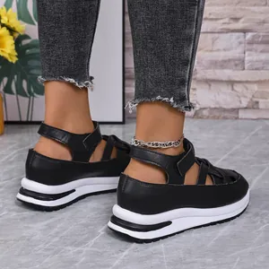 Close-up detail of black platform Roman sandals featuring Velcro straps and white soles