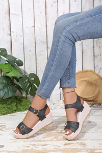 Detail view of black buckled wedge sandals with textured platform and cork-style heel.