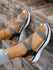 Nahaufnahme von Damen-Plateausandalen mit schwarz-weiß geflochtenen Riemen für den Sommer.