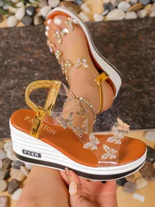 Close-up showing shiny rhinestone butterfly details on summer wedge sandals with clear straps