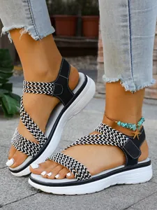Nahaufnahme der flachen Damen-Strandsandalen mit schwarz-weiß geflochtenen Riemen