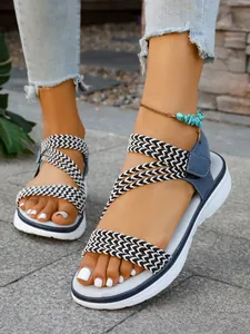 Detailansicht der stylischen flachen Sandalen mit Webriemen für Damen auf Steinpflaster