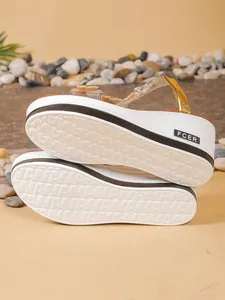 Detail view of white wedge sandal outsoles featuring rhinestone butterfly accents.