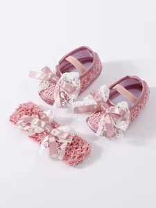 Detail view of pink lace baby shoes and matching bow headband set for newborns