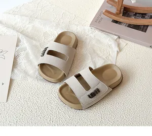 Detail view of beige children's Birkenstock style slippers with uim logo on soft texture